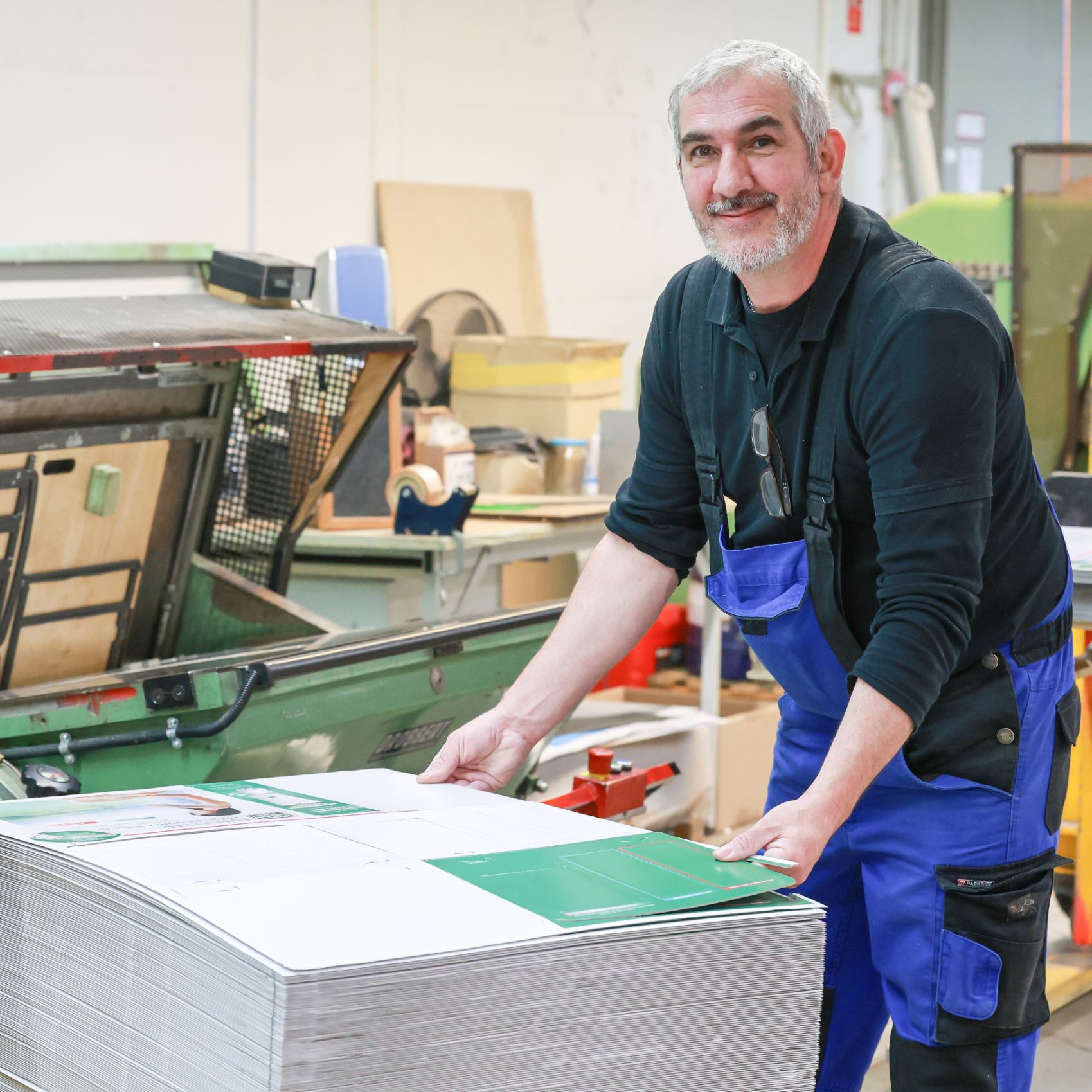 zufriedener Mitarbeiter stapelt Bögen zur Weiterverarbeitung